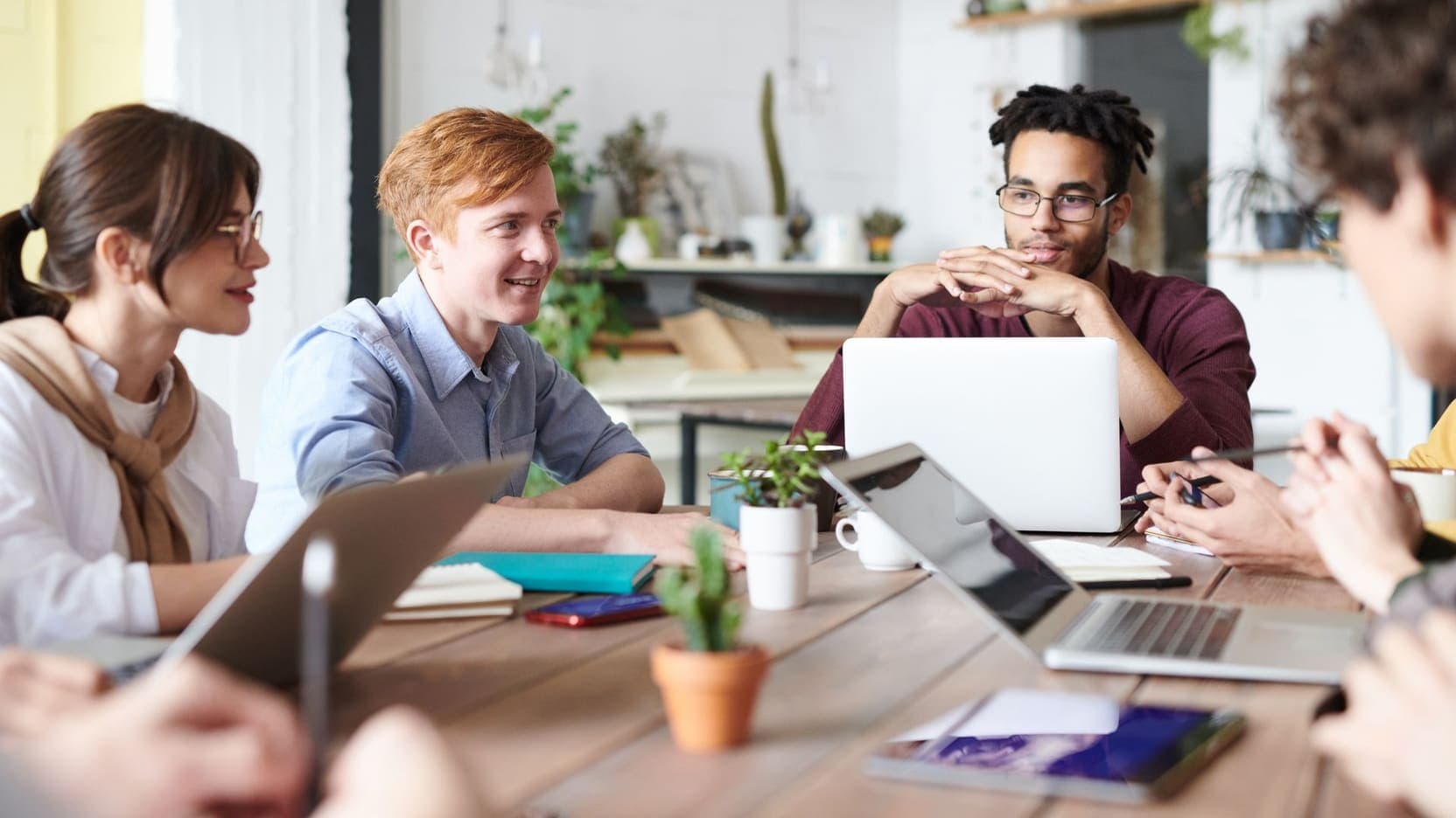 A team collaborating around laptops in a bright workspace